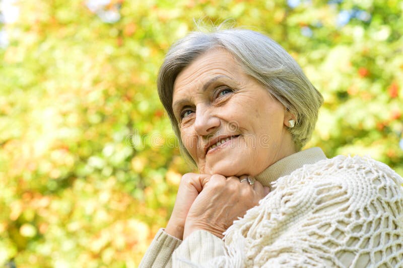 Ritratto della donna anziana sorridente piacevole che posa nella foresta fotografia stock libera da diritti Ritratto della donna anziana sorridente piacevole che posa nella foresta fotografia stock libera da diritti