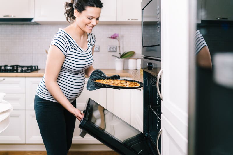 Ritratto della donna incinta che prepara pizza a casa immagini stock Ritratto della donna incinta che prepara pizza a casa immagini stock