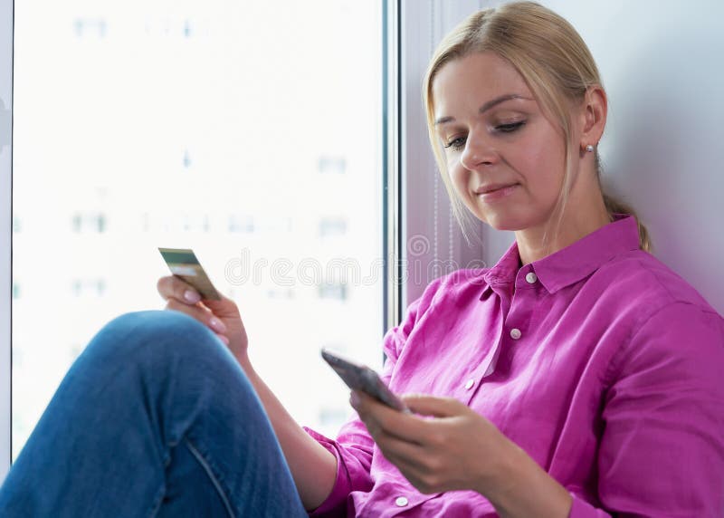 Ritratto della donna sorridente che tiene la carta di credito in sua mano mentre comperando online fotografia stock Ritratto della donna sorridente che tiene la carta di credito in sua mano mentre comperando online fotografia stock