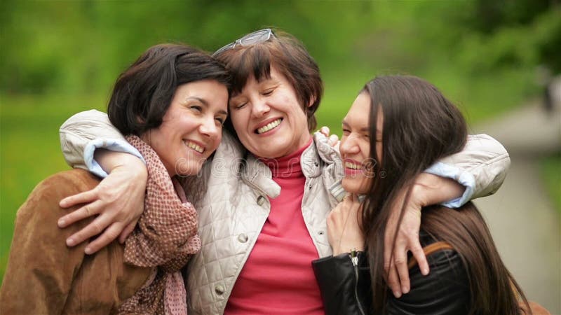 Ritratto della famiglia adorabile felice nel parco Le sorelle sorridenti stanno abbracciando la loro madre all'aperto