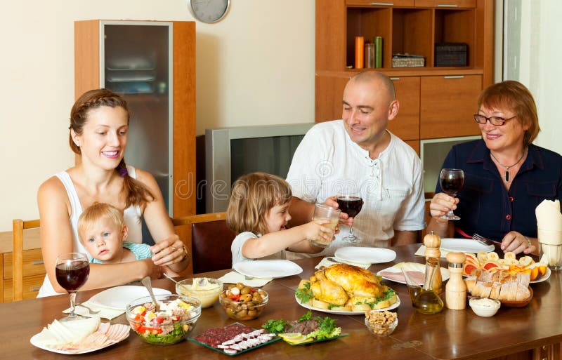 Ritratto della famiglia felice insieme sopra il tavolo da pranzo che mangia pulcino fotografie stock libere da diritti Ritratto della famiglia felice insieme sopra il tavolo da pranzo che mangia pulcino fotografie stock libere da diritti