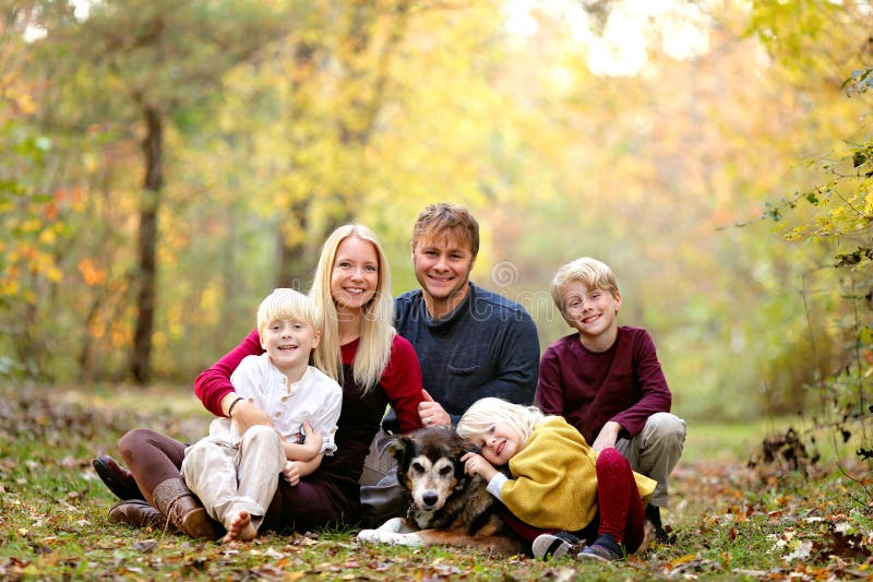 Ritratto della felice famiglia di madre e padre e dei loro carini bambini sorridenti e del loro cane da compagnia fuori fotografia stock Ritratto della felice famiglia di madre e padre e dei loro carini bambini sorridenti e del loro cane da compagnia fuori fotografia stock