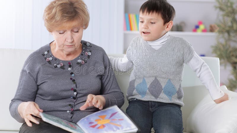 Ritratto della nonna e del nipote che leggono un libro nella scuola materna fotografie stock Ritratto della nonna e del nipote che leggono un libro nella scuola materna fotografie stock