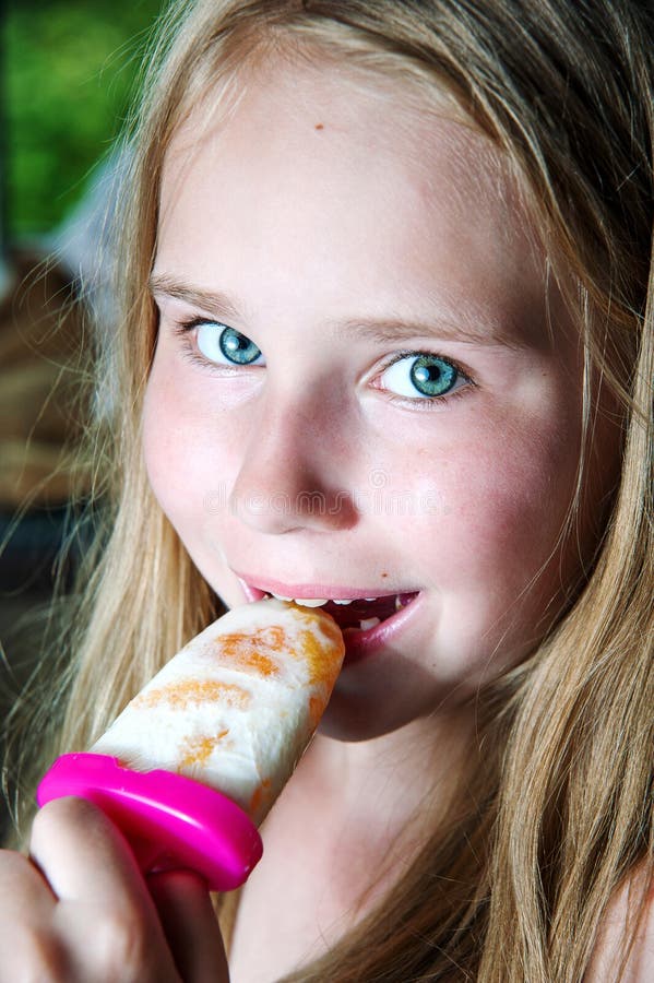 Ritratto della ragazza che mangia ghiacciolo e sorriso fotografie stock Ritratto della ragazza che mangia ghiacciolo e sorriso fotografie stock