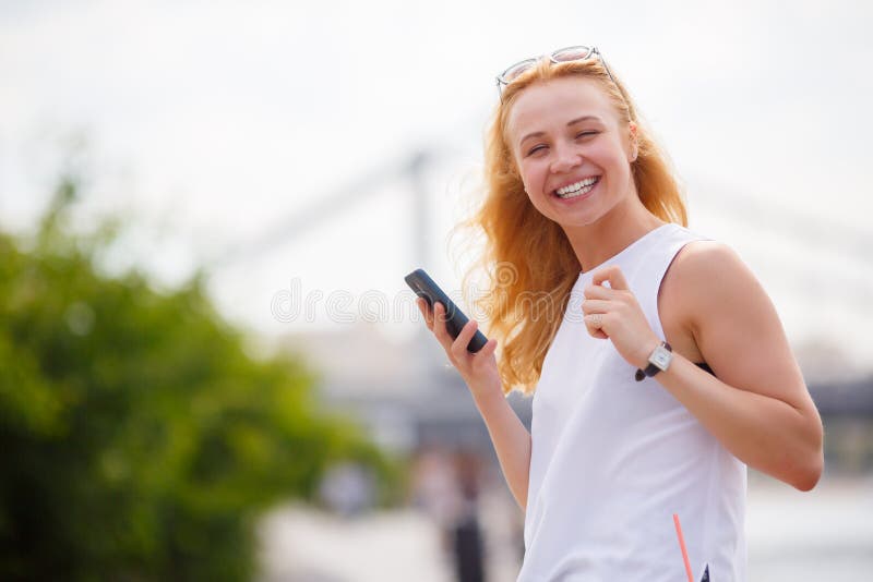 Ritratto della ragazza sorridente con lo smartphone della tenuta dei capelli ricci immagini stock libere da diritti Ritratto della ragazza sorridente con lo smartphone della tenuta dei capelli ricci immagini stock libere da diritti