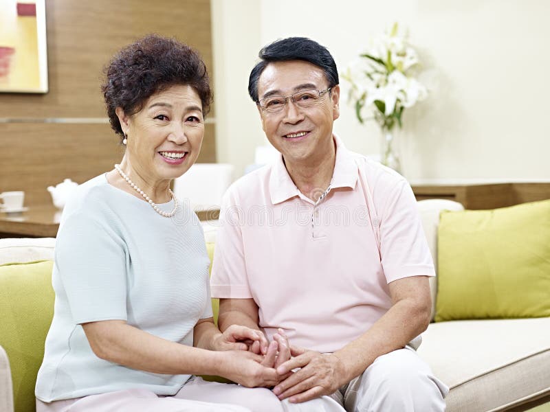 Portrait of a senior asian couple sitting on couch looking at camera smiling. Portrait of a senior asian couple sitting on couch looking at camera smiling