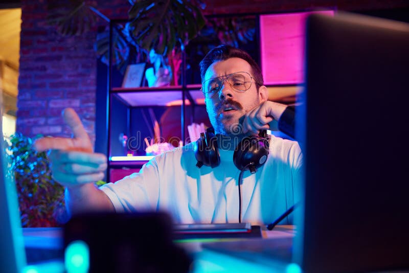 Ritratto dello streaming con configurazione microfono professionale che interagisce con il pubblico in chat live in neon lit homes fotografie stock