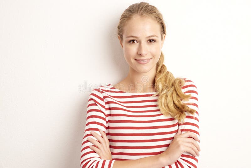 Ritratto dello studio del lookig grazioso della giovane donna alla macchina fotografica ed a sorridere mentre stando al fondo bia fotografie stock libere da diritti Ritratto dello studio del lookig grazioso della giovane donna alla macchina fotografica ed a sorridere mentre stando al fondo bia fotografie stock libere da diritti