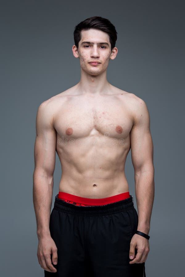 Ritratto dello studio di giovane uomo caucasico castana sulla posa grigia del fondo Tema di pubertà, pelle di problema, acne teen immagine stock Ritratto dello studio di giovane uomo caucasico castana sulla posa grigia del fondo Tema di pubertà, pelle di problema, acne teen immagine stock