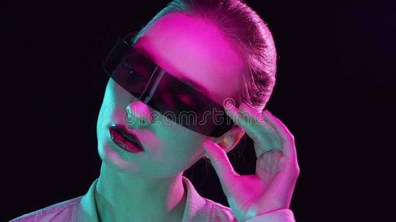 Ritratto di adolescente in stile cyberpunk. giovane donna in posa con occhiali da sole futuristici. luce da studio creativa. archivi video