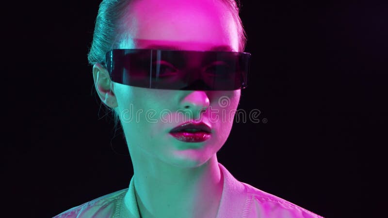 Ritratto di adolescente in stile cyberpunk. giovane donna in posa con occhiali da sole futuristici. luce da studio creativa. stock footage