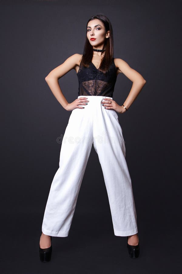 Ritratto di bella donna castana in una blusa nera e nei pantaloni bianchi, Colpo della foto di modo fotografia stock Ritratto di bella donna castana in una blusa nera e nei pantaloni bianchi, Colpo della foto di modo fotografia stock