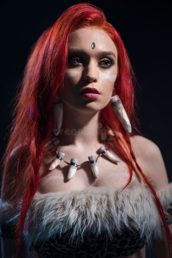 Ritratto di bella donna dai capelli rossi in abbigliamento di età della pietra con il carcanet dei denti immagine stock Ritratto di bella donna dai capelli rossi in abbigliamento di età della pietra con il carcanet dei denti immagine stock