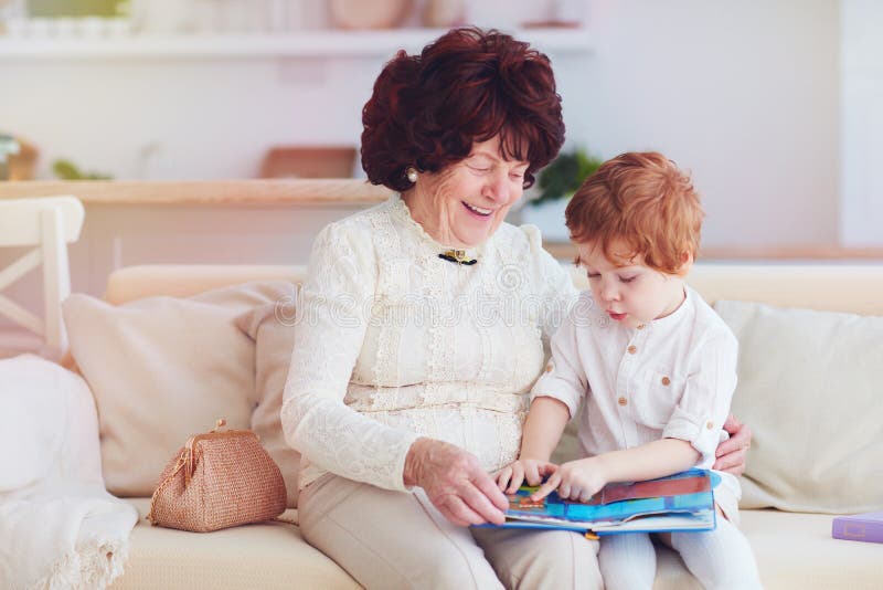 Ritratto di bella donna matura 80 anni con la sua pronipote a casa, leggente insieme libro educativo fotografie stock Ritratto di bella donna matura 80 anni con la sua pronipote a casa, leggente insieme libro educativo fotografie stock