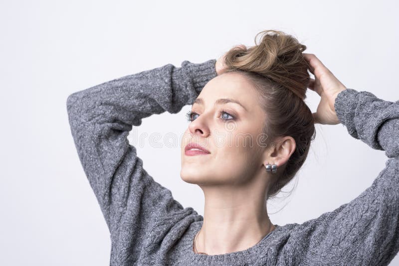 Ritratto di bella giovane donna indipendente che fa la pettinatura del panino dei capelli lei stessa fotografia stock Ritratto di bella giovane donna indipendente che fa la pettinatura del panino dei capelli lei stessa fotografia stock