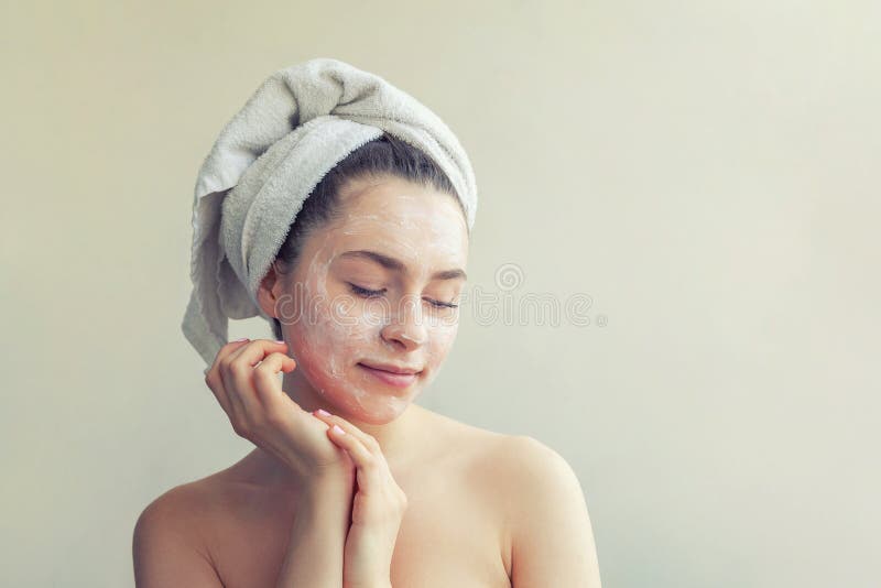 Ritratto di bellezza della donna in asciugamano sulla testa con la maschera di nutrizione bianca o sulla crema sul fronte, fondo fotografia stock Ritratto di bellezza della donna in asciugamano sulla testa con la maschera di nutrizione bianca o sulla crema sul fronte, fondo fotografia stock