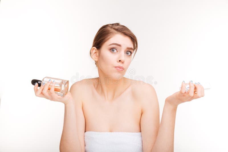 Ritratto di bellezza della giovane donna confusa che sceglie fra due parfums fotografia stock Ritratto di bellezza della giovane donna confusa che sceglie fra due parfums fotografia stock