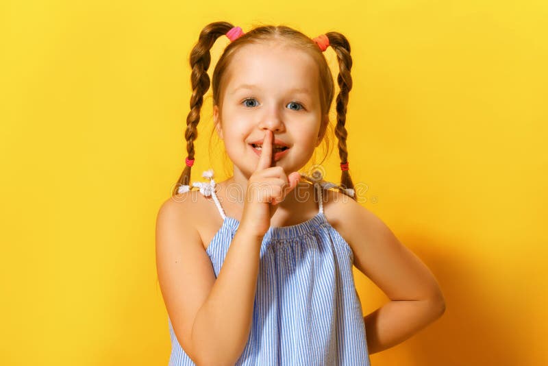 Ritratto di chiusura di una bambina carina e attraente che mostra un segno di sfondo giallo immagini stock Ritratto di chiusura di una bambina carina e attraente che mostra un segno di sfondo giallo immagini stock