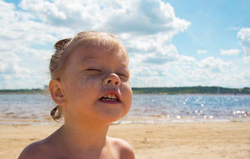 Ritratto di delizioso bambino caucasico a causa del sole e dell'estate sulla spiaggia vicino al fiume