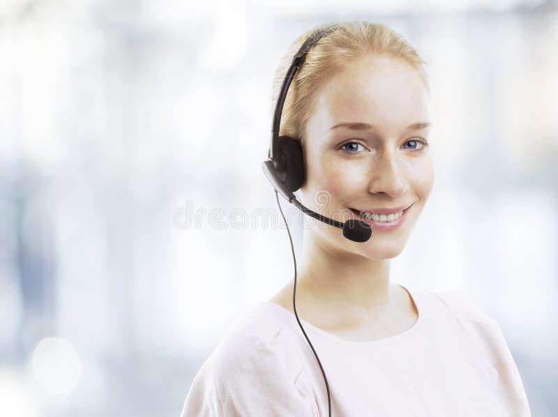 Giovane agente femminile sicuro di servizio di assistenza al cliente con la cuffia avricolare fotografia stock Giovane agente femminile sicuro di servizio di assistenza al cliente con la cuffia avricolare fotografia stock