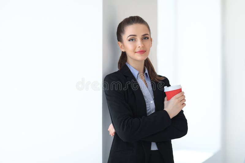 Ritratto di giovane bella donna di affari con la tazza di caffè dentro immagini stock libere da diritti Ritratto di giovane bella donna di affari con la tazza di caffè dentro immagini stock libere da diritti