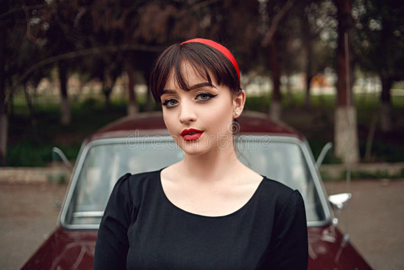 Ritratto di giovane bella ragazza in vestiti d'annata accanto ad una retro automobile fotografia stock libera da diritti Ritratto di giovane bella ragazza in vestiti d'annata accanto ad una retro automobile fotografia stock libera da diritti