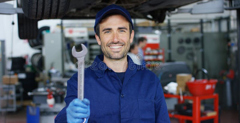 Ritratto di giovane bello meccanico di automobile in un'officina riparazioni dell'automobile, mani con una chiave Concetto: ripar immagine stock libera da diritti Ritratto di giovane bello meccanico di automobile in un'officina riparazioni dell'automobile, mani con una chiave Concetto: ripar immagine stock libera da diritti