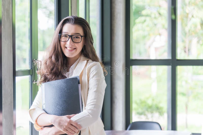 Ritratto di giovane donna di affari che smileing e che tiene documento, Successo nel concetto di affari, di lavoro e di istruzion fotografia stock Ritratto di giovane donna di affari che smileing e che tiene documento, Successo nel concetto di affari, di lavoro e di istruzion fotografia stock
