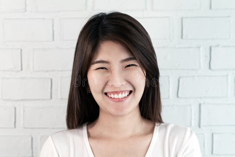 Ritratto di giovane donna castana asiatica attraente che esamina macchina fotografica che sorride con il concetto sicuro e positi immagine stock libera da diritti Ritratto di giovane donna castana asiatica attraente che esamina macchina fotografica che sorride con il concetto sicuro e positi immagine stock libera da diritti