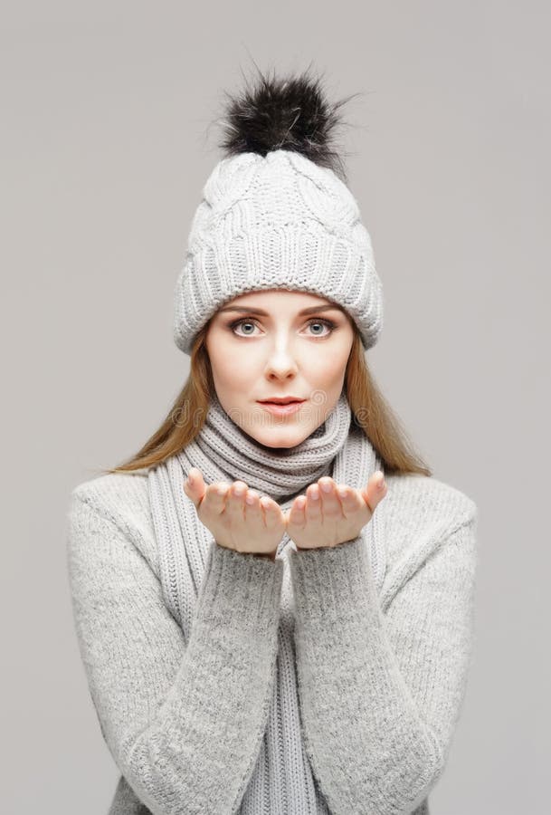 Ritratto di giovane e bella donna in un cappello di inverno sopra fondo grigio immagini stock libere da diritti Ritratto di giovane e bella donna in un cappello di inverno sopra fondo grigio immagini stock libere da diritti
