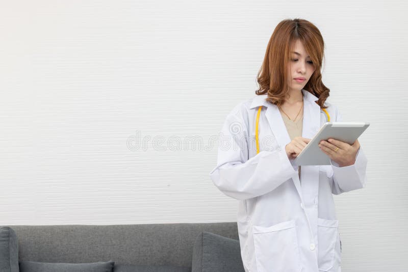Ritratto di giovane medico femminile asiatico della medicina che sta e che tiene compressa nell'ufficio dell'ospedale fotografia stock libera da diritti Ritratto di giovane medico femminile asiatico della medicina che sta e che tiene compressa nell'ufficio dell'ospedale fotografia stock libera da diritti