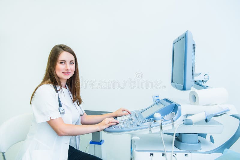 Ritratto di giovane medico sorridente, specialista di ultrasuono che esamina macchina fotografica e che per mezzo della macchina fotografia stock libera da diritti Ritratto di giovane medico sorridente, specialista di ultrasuono che esamina macchina fotografica e che per mezzo della macchina fotografia stock libera da diritti