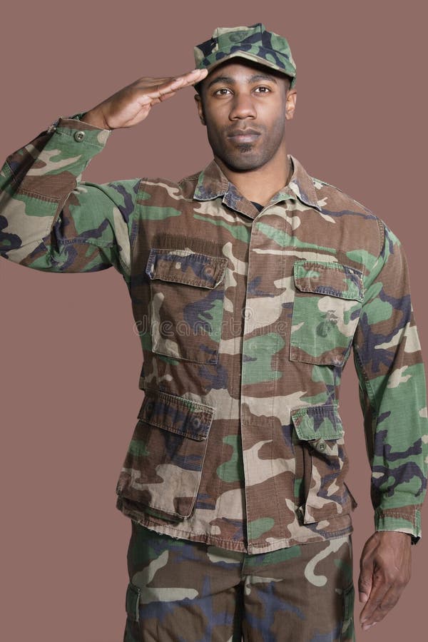 Ritratto di giovane soldato degli Stati Uniti Marine Corps dell'afroamericano che saluta sopra il fondo marrone fotografie stock libere da diritti Ritratto di giovane soldato degli Stati Uniti Marine Corps dell'afroamericano che saluta sopra il fondo marrone fotografie stock libere da diritti