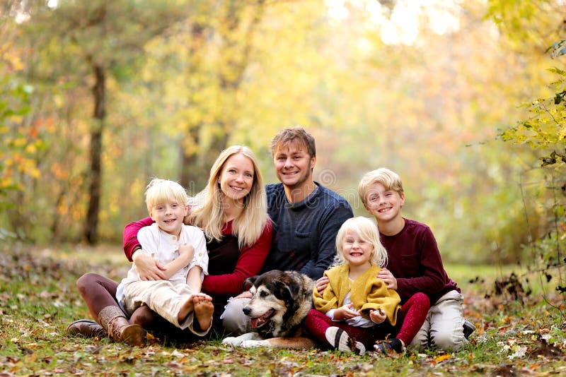 Ritratto di Happy Young Family con tre bambini carini e sorridenti e il loro cane da compagnia il giorno dell'autunno immagini stock Ritratto di Happy Young Family con tre bambini carini e sorridenti e il loro cane da compagnia il giorno dell'autunno immagini stock