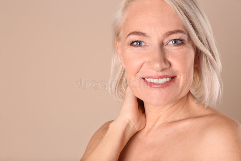 Ritratto di incantare donna matura con la bella pelle sana del fronte e trucco naturale su fondo beige, primo piano immagine stock Ritratto di incantare donna matura con la bella pelle sana del fronte e trucco naturale su fondo beige, primo piano immagine stock