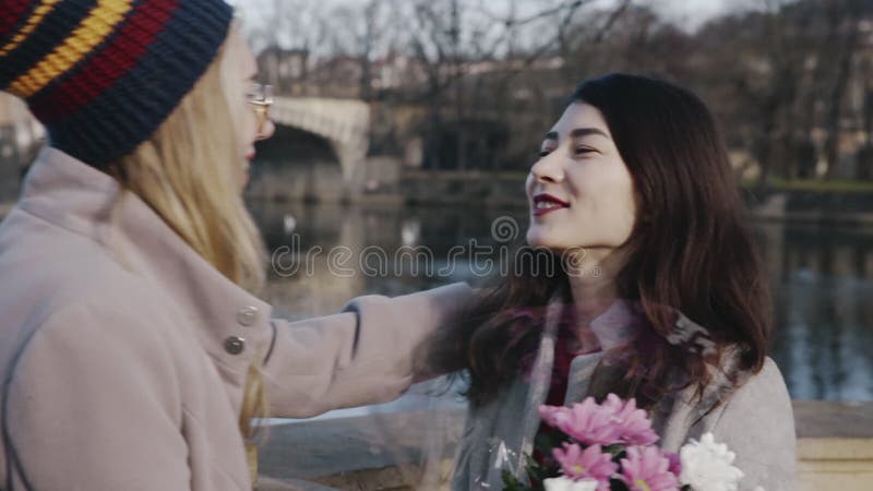 Ritratto di lesbiche felici in data. ragazza bionda con un mucchio di fiori alla ragazza asiatica. giovane omosessuale video d archivio