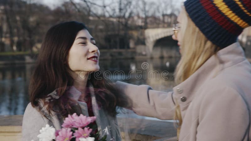 Ritratto di lesbiche felici in data. ragazza bionda con un mucchio di fiori alla ragazza asiatica. giovane omosessuale stock footage