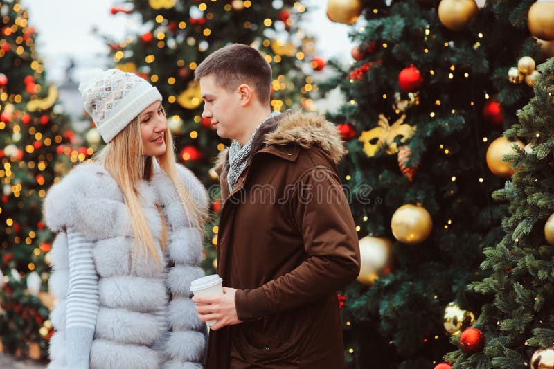 ritratto di natale delle coppie felici con vin brulé o tè caldo che cammina sulle vie della città decorate per le feste fotografia stock libera da diritti ritratto di natale delle coppie felici con vin brulé o tè caldo che cammina sulle vie della città decorate per le feste fotografia stock libera da diritti