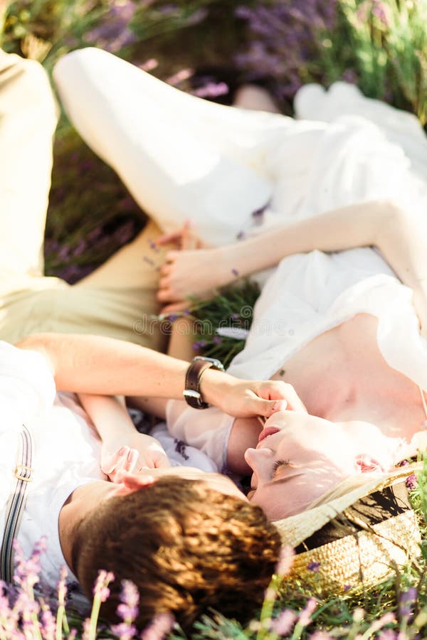 Ritratto di stordimento della sposa e dello sposo che si trovano in un giacimento della lavanda immagine stock Ritratto di stordimento della sposa e dello sposo che si trovano in un giacimento della lavanda immagine stock