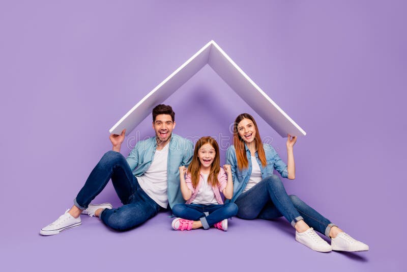 Ritratto di tre membri della famiglia seduti al piano sotto un tetto nuovo indossa abiti casuali sfondo viola immagine stock libera da diritti Ritratto di tre membri della famiglia seduti al piano sotto un tetto nuovo indossa abiti casuali sfondo viola immagine stock libera da diritti
