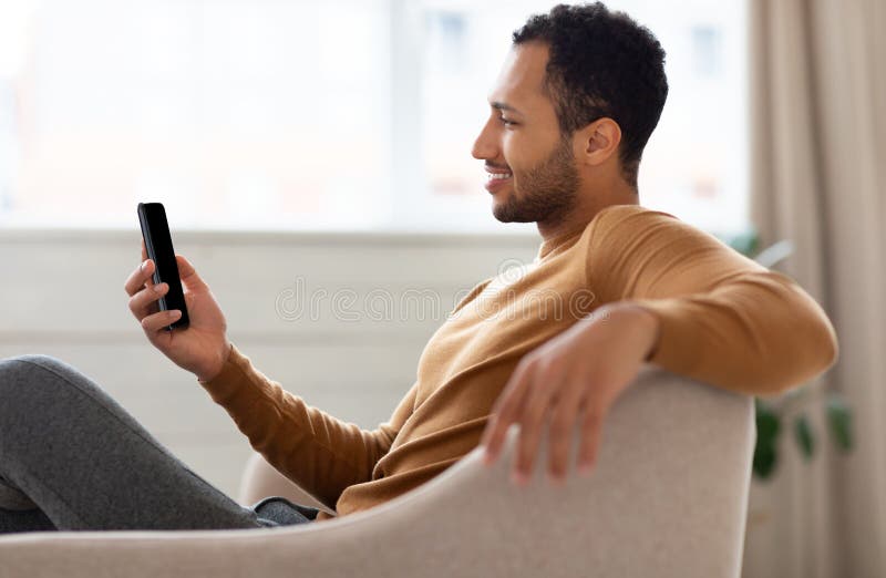 Ritratto di un arabo sorridente che usa smartphone a casa fotografie stock libere da diritti