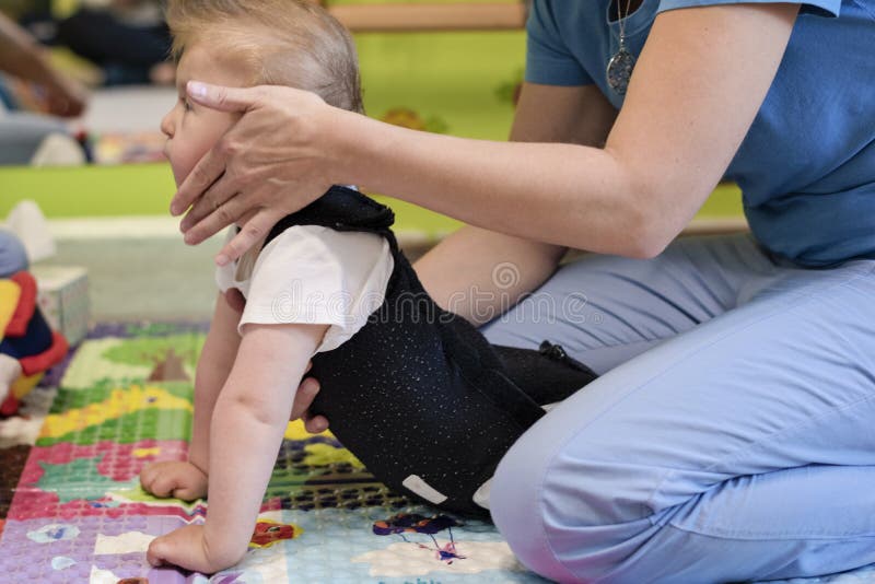 Portrait of a child with cerebral palsy on physiotherapy in a children therapy center. Boy with disability has therapy by doing exercises with physiotherapists in rehabitation centre. Portrait of a child with cerebral palsy on physiotherapy in a children therapy center. Boy with disability has therapy by doing exercises with physiotherapists in rehabitation centre