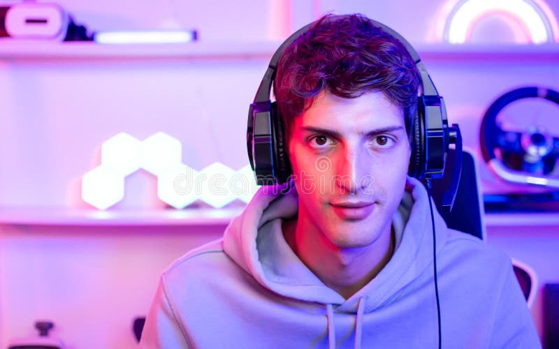 Ritratto di un bel giovane gioco maschile online seducente che sorride guardando la telecamera si gioca in una stanza con fotografie stock libere da diritti
