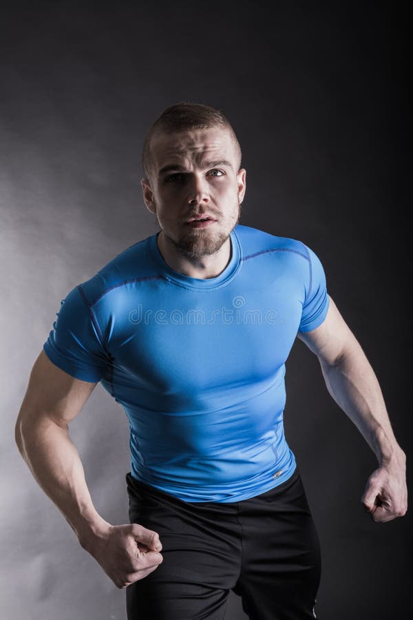 Ritratto di un giovane aggressivo muscolare che sta nello studio sul fondo nero dello studio fotografie stock Ritratto di un giovane aggressivo muscolare che sta nello studio sul fondo nero dello studio fotografie stock