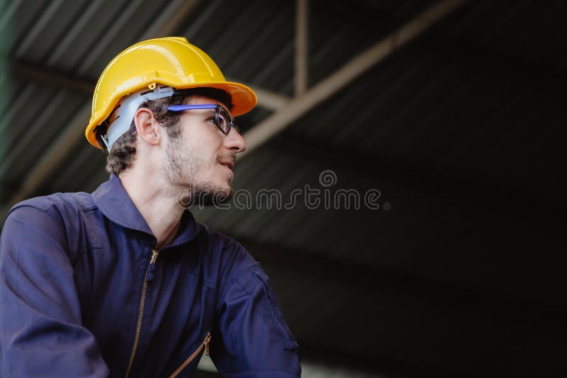 Ritratto di un giovane americano felice lavoratore in borghese hardhat helmet, ingegnere in abiti di sicurezza, con una copia dell fotografia stock libera da diritti