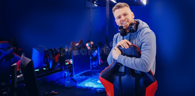 Ritratto di un giovane uomo felice, giocatore professionista dei giochi online con cuffie a colori con banner fotografia stock libera da diritti