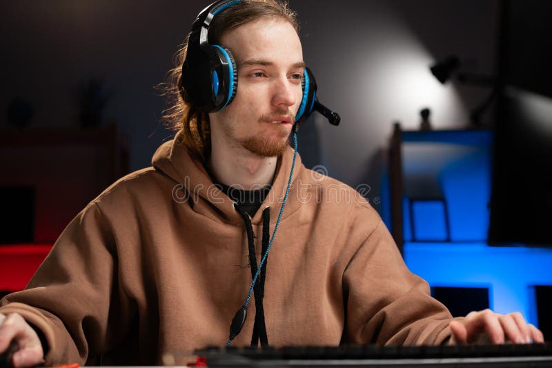 Ritratto di un hipster con cuffie gioco a casa. giovane giocatore professionista gioca in streaming nel videogioco online. online immagine stock