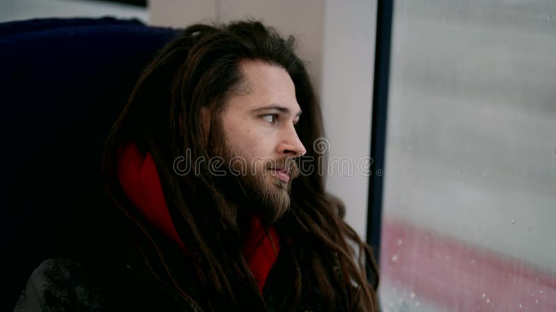 Ritratto di un omossessuale barbuto carino su un treno che guarda fuori dalla finestra. stock footage