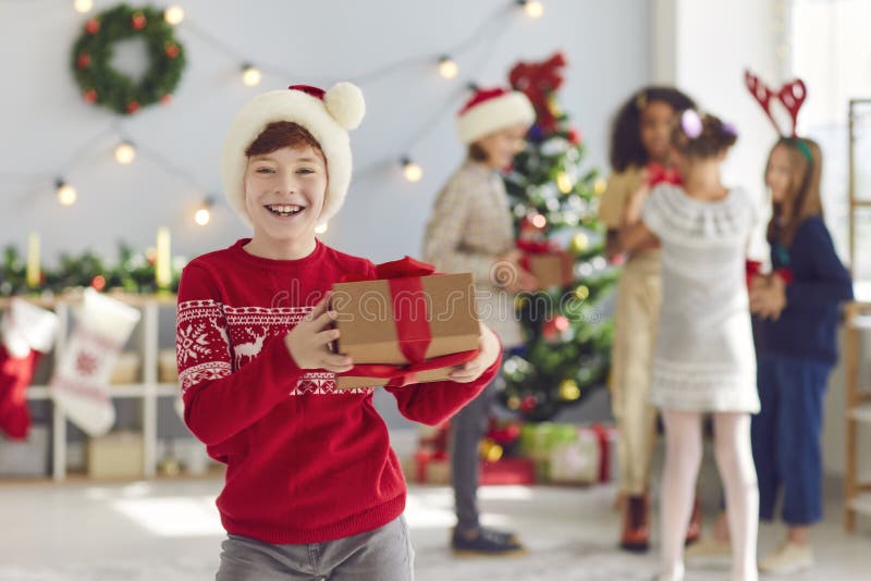 Ritratto di un ragazzo felice con un natale nelle mani in una stanza con decorazioni natalizie. fotografia stock