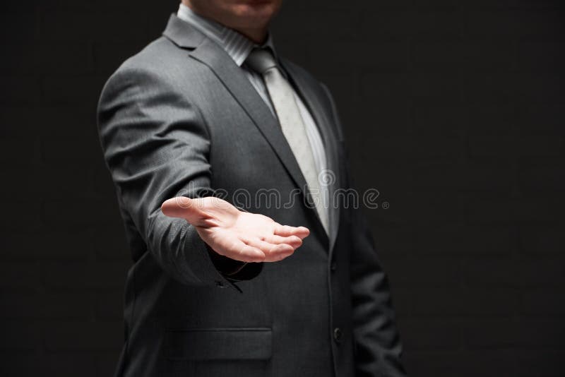 Ritratto di un uomo d'affari che mostra una palma di mano per mostrare qualcosa vestito in costume grigio di sfondo